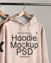 Two Hoodies on a Wooden Hanger Against a Plain Background Mockup