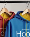 Two Hoodies on a Wooden Hanger Against a Plain Background Mockup