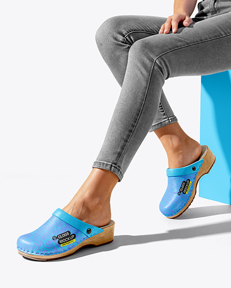 Pair of Clogs on Woman's Legs Sitting on Block Mockup - Merchandise mockup