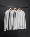 Three Sweatshirts on a Black Rack Against a Plain Background Mockup