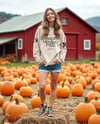 Young Woman in Sweatshirt Standing on Hay Block with Pumpkins Around Mockup
