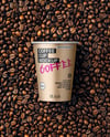 12oz Paper Cup on a Stack of Coffee Beans Mockup