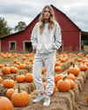 Young Woman in Sweatshirt and Joggers Standing on Hay Block at Pumpkin Patch Mockup