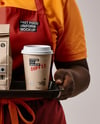 Female Fast Food Worker in Uniform with Paper Bag & Coffee Cup Mockup